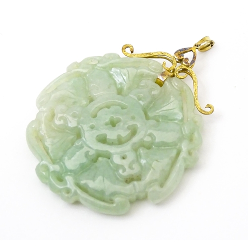 740 - An Oriental carved jade pendant with yellow metal mounts marked 585. Approx. 2 3/4