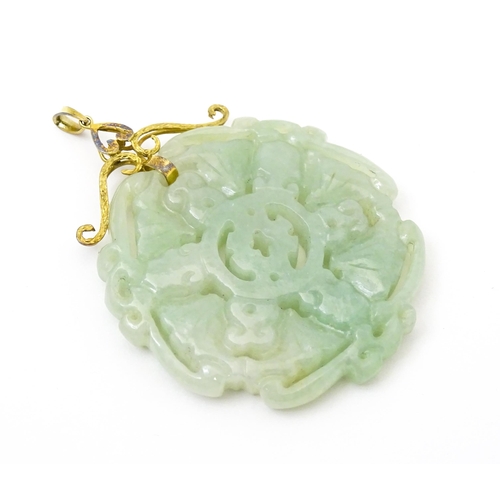 740 - An Oriental carved jade pendant with yellow metal mounts marked 585. Approx. 2 3/4