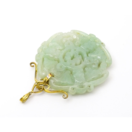 740 - An Oriental carved jade pendant with yellow metal mounts marked 585. Approx. 2 3/4