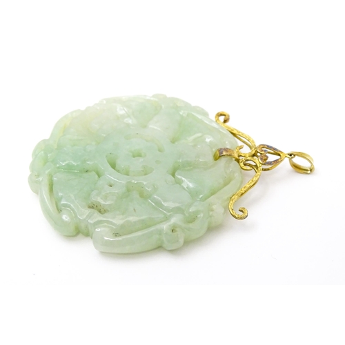 740 - An Oriental carved jade pendant with yellow metal mounts marked 585. Approx. 2 3/4