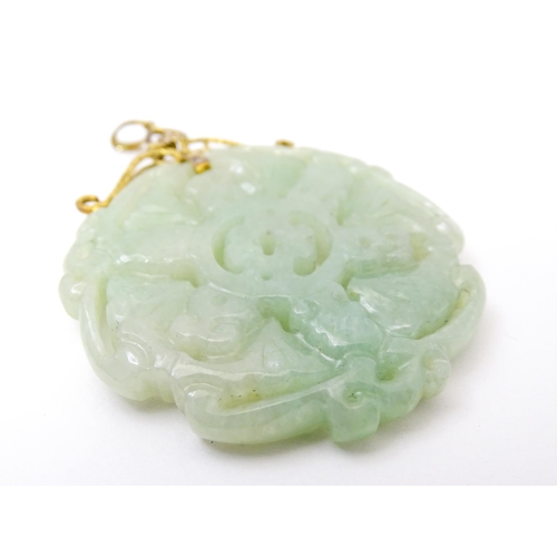 740 - An Oriental carved jade pendant with yellow metal mounts marked 585. Approx. 2 3/4