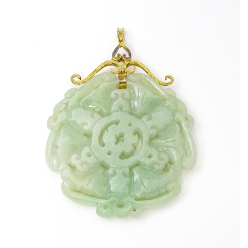 740 - An Oriental carved jade pendant with yellow metal mounts marked 585. Approx. 2 3/4