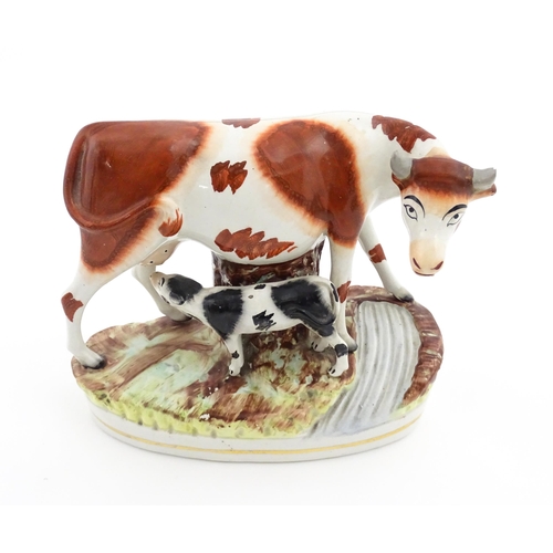 44 - A Staffordshire pottery model of a cow and calf on a naturalistic base. Approx. 7