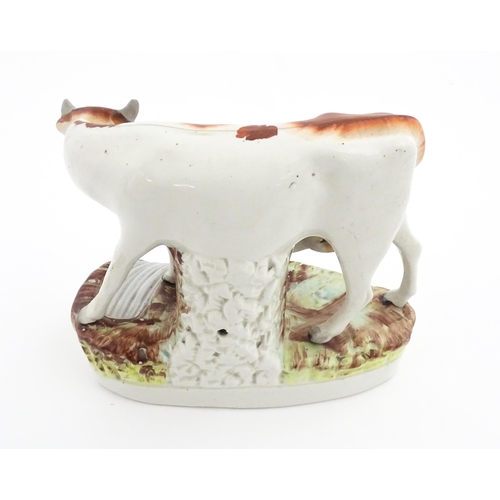 44 - A Staffordshire pottery model of a cow and calf on a naturalistic base. Approx. 7