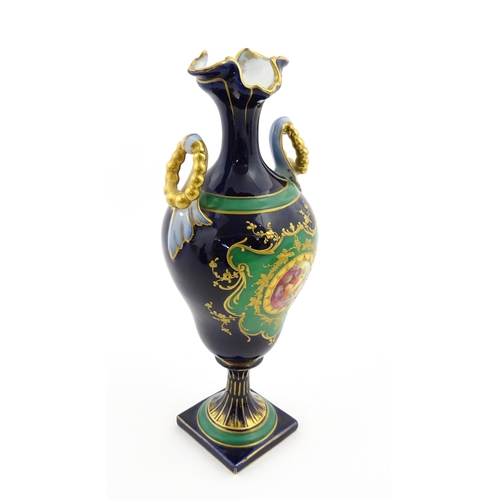 59 - A Coalport style cabinet vase with twin handles and shaped rim, decorated with a hand painted vignet... 