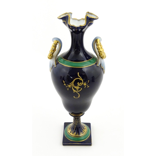 59 - A Coalport style cabinet vase with twin handles and shaped rim, decorated with a hand painted vignet... 