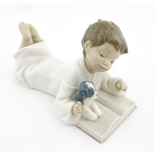 76 - A Nao figure Repeat After Me, modelled as a young boy reading with a puppy. Marked under. Approx. 4