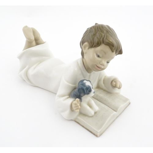 76 - A Nao figure Repeat After Me, modelled as a young boy reading with a puppy. Marked under. Approx. 4