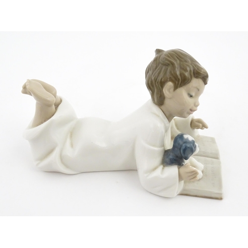 76 - A Nao figure Repeat After Me, modelled as a young boy reading with a puppy. Marked under. Approx. 4