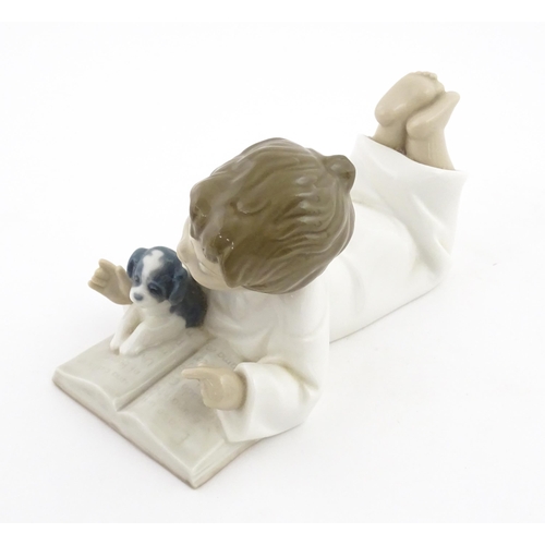 76 - A Nao figure Repeat After Me, modelled as a young boy reading with a puppy. Marked under. Approx. 4