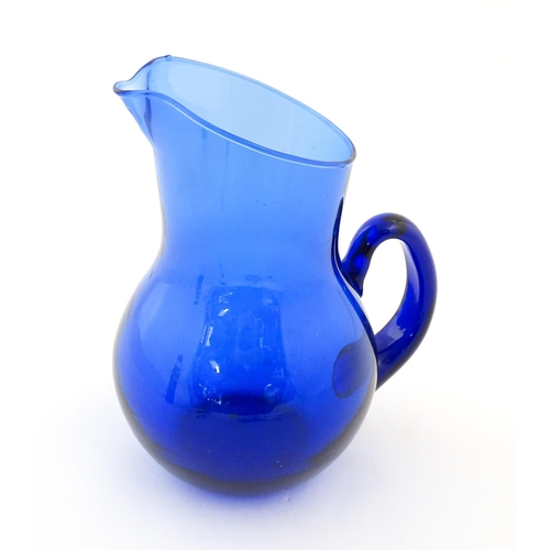 190 - A blue glass water jug with loop handle. Approx. 9