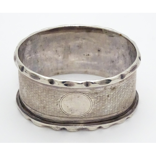 388 - A silver napkin ring hallmarked Birmingham 1929, maker Samuel Levi. Together with a glass caster wit... 