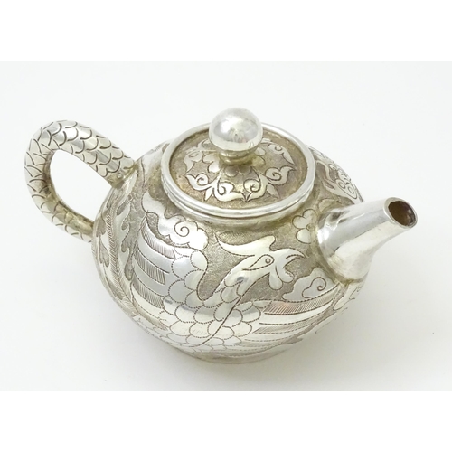 408 - A small Chinese export silver and white metal teapot with dragon and phoenix decoration. Marked unde... 