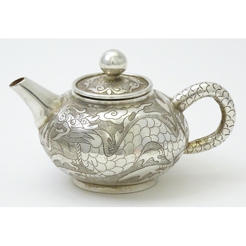 408 - A small Chinese export silver and white metal teapot with dragon and phoenix decoration. Marked unde... 