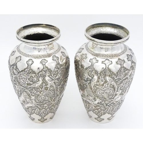 487 - A pair of Iranian / Persian silver vases decorated in relief with animals, birds and flowers. Possib... 