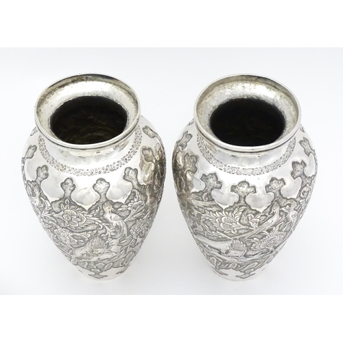 487 - A pair of Iranian / Persian silver vases decorated in relief with animals, birds and flowers. Possib... 