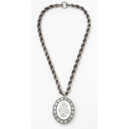 749 - Victorian silver oval locket with engraved floral decoration on white metal rope twist chain. Hallma... 