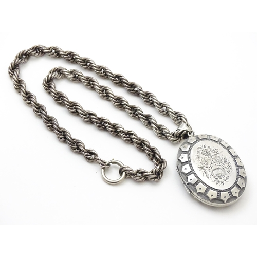 749 - Victorian silver oval locket with engraved floral decoration on white metal rope twist chain. Hallma... 