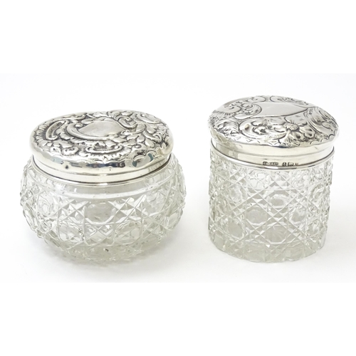 423 - Two cut glass dressing table jars with silver lids having embossed decoration, one hallmarked Birmin... 