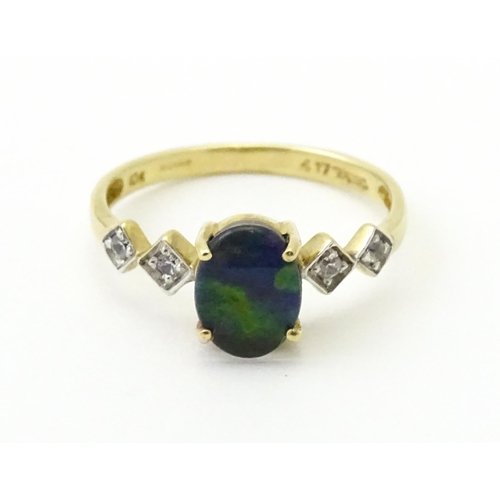 580 - A 9ct gold ring set with central ammolite flanked by white stones. Ring size approx. L