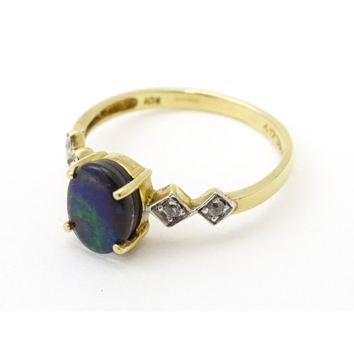 580 - A 9ct gold ring set with central ammolite flanked by white stones. Ring size approx. L