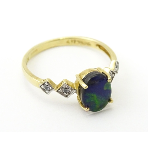 580 - A 9ct gold ring set with central ammolite flanked by white stones. Ring size approx. L