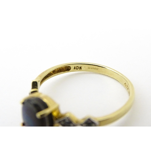 580 - A 9ct gold ring set with central ammolite flanked by white stones. Ring size approx. L