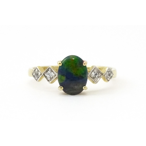 580 - A 9ct gold ring set with central ammolite flanked by white stones. Ring size approx. L