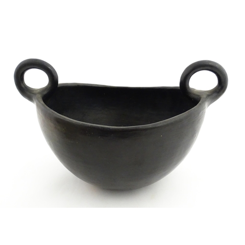 132 - A studio pottery terracotta bowl with black glaze and twin loop handles. Approx. 15