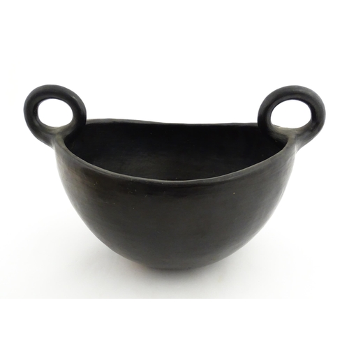 132 - A studio pottery terracotta bowl with black glaze and twin loop handles. Approx. 15