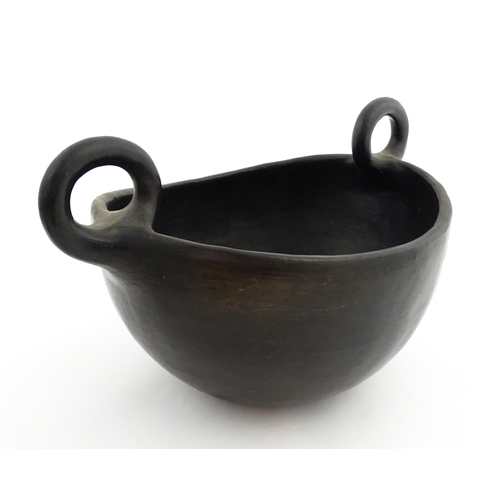 132 - A studio pottery terracotta bowl with black glaze and twin loop handles. Approx. 15