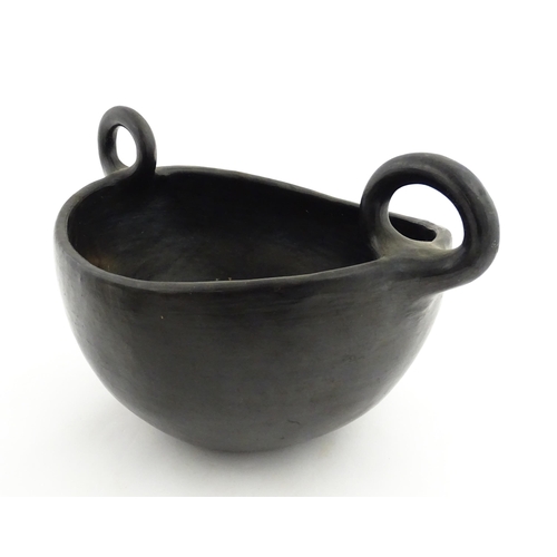 132 - A studio pottery terracotta bowl with black glaze and twin loop handles. Approx. 15