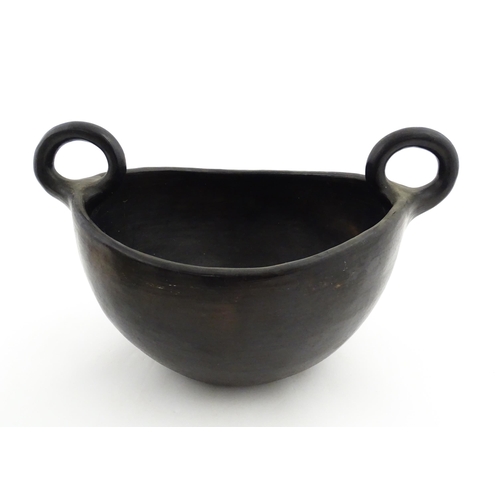 132 - A studio pottery terracotta bowl with black glaze and twin loop handles. Approx. 15