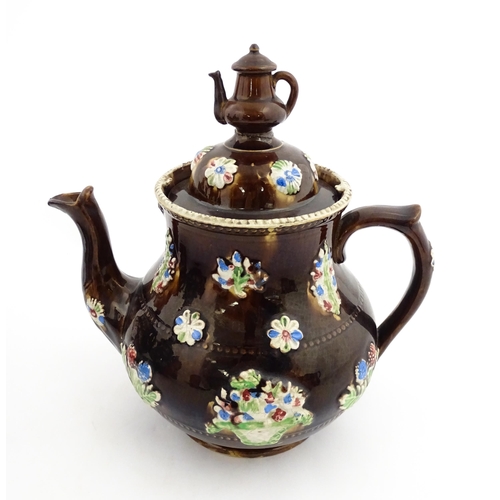 149 - A 19thC Measham bargeware teapot decorated with flowers in baskets and floral motifs. The lid with t... 