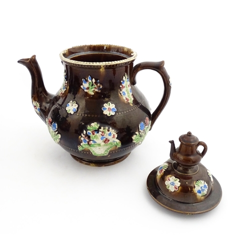 149 - A 19thC Measham bargeware teapot decorated with flowers in baskets and floral motifs. The lid with t... 