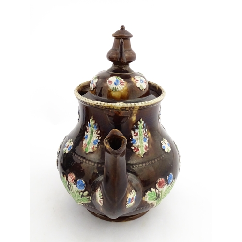 149 - A 19thC Measham bargeware teapot decorated with flowers in baskets and floral motifs. The lid with t... 