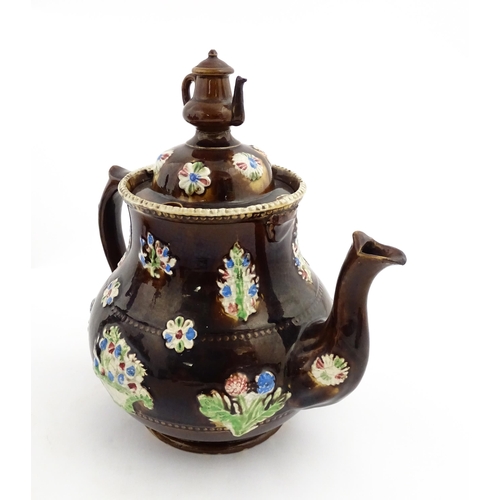 149 - A 19thC Measham bargeware teapot decorated with flowers in baskets and floral motifs. The lid with t... 