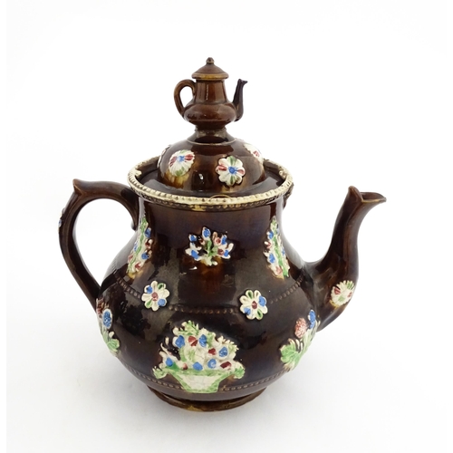 149 - A 19thC Measham bargeware teapot decorated with flowers in baskets and floral motifs. The lid with t... 