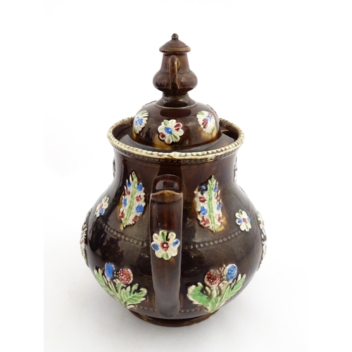 149 - A 19thC Measham bargeware teapot decorated with flowers in baskets and floral motifs. The lid with t... 