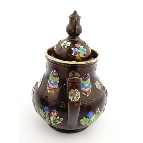 151 - A 19thC Measham bargeware teapot decorated with birds, flowers and foliage, bearing a plaque for 'A ... 