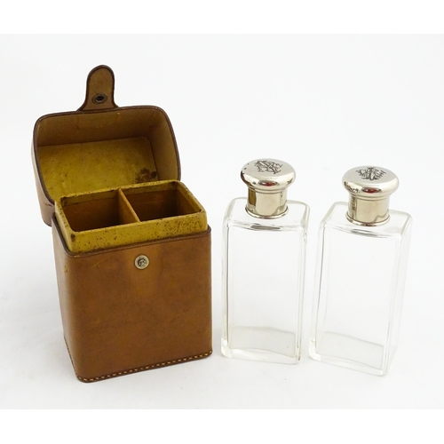 1080 - A cased pair of 20thC glass scent bottles / perfume flasks with glass stoppers and silver plate lids... 