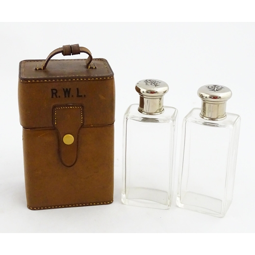 1080 - A cased pair of 20thC glass scent bottles / perfume flasks with glass stoppers and silver plate lids... 