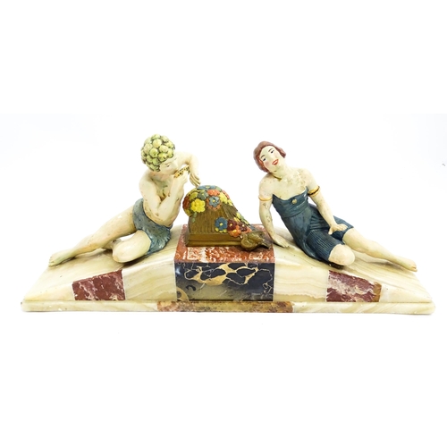 1226 - A 20thC Art Deco style sculpture modelled as two reclining figures with flowers and a bird upon a ma... 