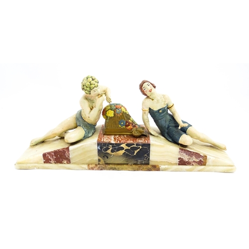 1226 - A 20thC Art Deco style sculpture modelled as two reclining figures with flowers and a bird upon a ma... 