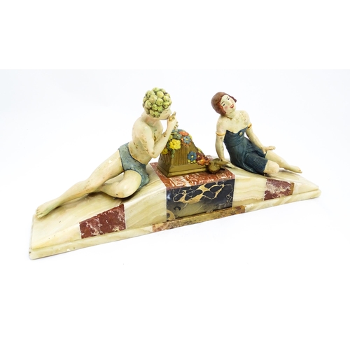 1226 - A 20thC Art Deco style sculpture modelled as two reclining figures with flowers and a bird upon a ma... 