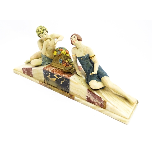 1226 - A 20thC Art Deco style sculpture modelled as two reclining figures with flowers and a bird upon a ma... 