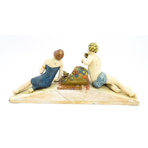 1226 - A 20thC Art Deco style sculpture modelled as two reclining figures with flowers and a bird upon a ma... 