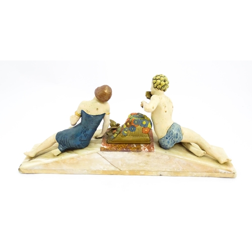 1226 - A 20thC Art Deco style sculpture modelled as two reclining figures with flowers and a bird upon a ma... 