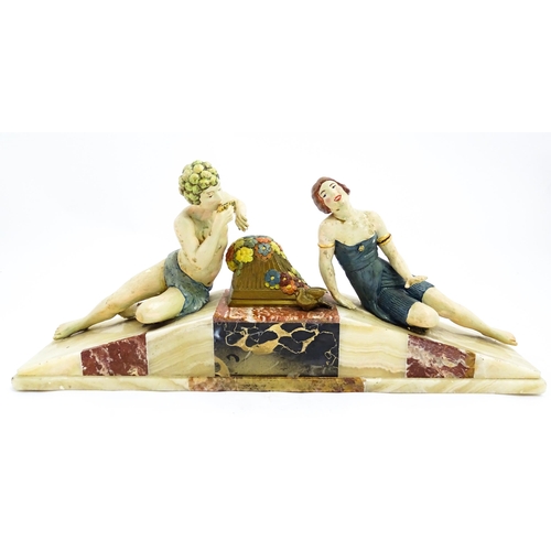 1226 - A 20thC Art Deco style sculpture modelled as two reclining figures with flowers and a bird upon a ma... 