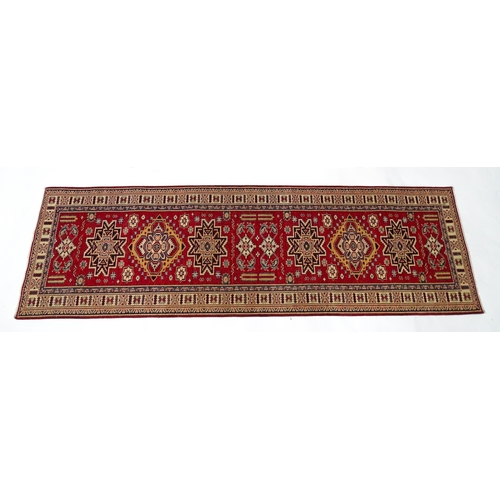 1317 - Carpet / Rug : A red ground runner decorated with repeating geometric motifs within banded geometric... 